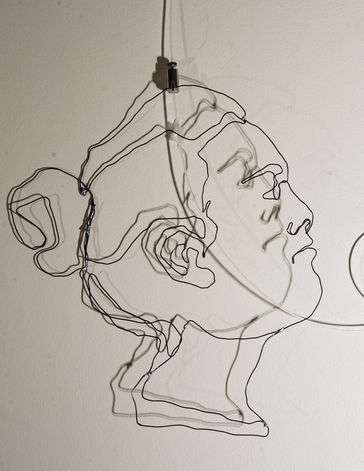 A wire sculpture of a feminine face and curly hair