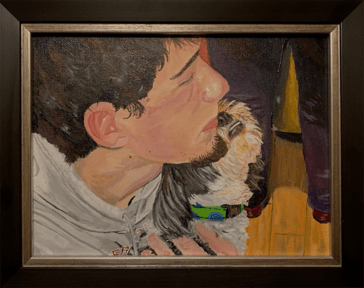 A painting in a black frame  that depicts a boy with a small goatee and a cut off sweatshirt. He is holding a small dog with a vibrant collar.