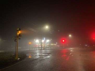 A foggy, wet evening caught at a red and yellow light. 