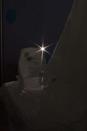 White mask with holes with flash of light behind it
