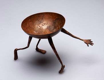 A hammered copper bowl with hand forged arms and legs. The arms and legs were then riveted to the bowl