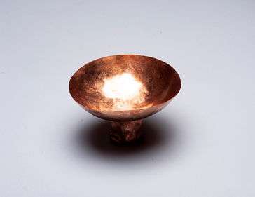 Copper bowl with a foot attached to it.