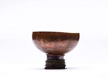 copper bowl sitting on base with spinnable twisted brass hoops
