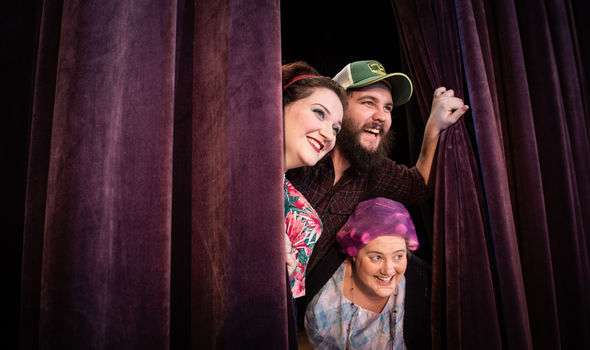 students peek out from a stage curtain
